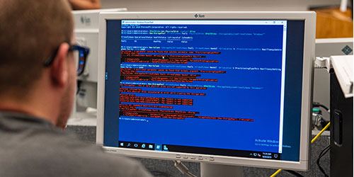 A male IT student works on computer code