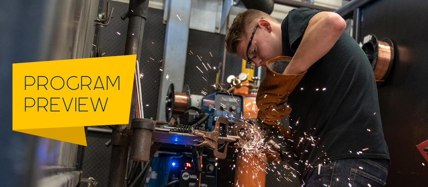 A student uses an angle grinder on a piece of metal in the welding lab.
