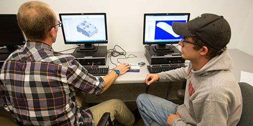 Two CAD students work on a design on a computer.