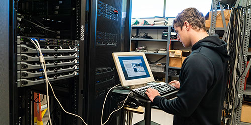 An NICC network student installs a new server in a rack.