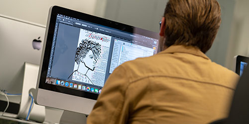 An NICC graphic design student designs a poster in the business lab.
