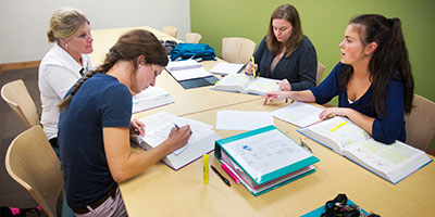 A group of four female students work together in a study room.