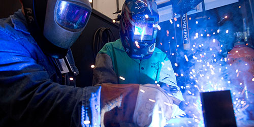 Two welding students practice in the lab.