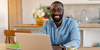 Adult man smiling while working on a laptop
