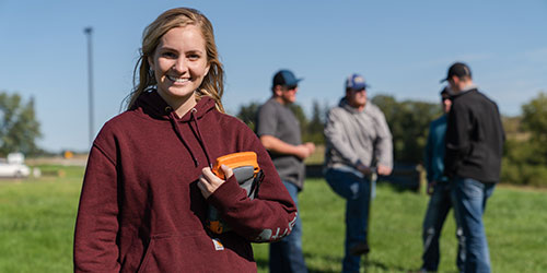 Female Ag student in foreground with drone control and male students in the background