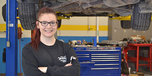Female Auto Student works on a lifted vehicle