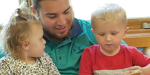 Male education student reads to two young kids