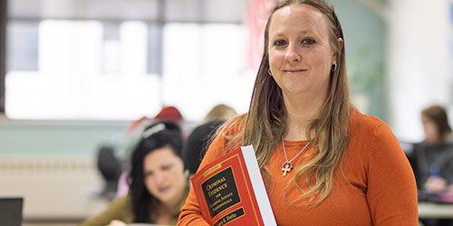 A female criminal justice student poses with a text book