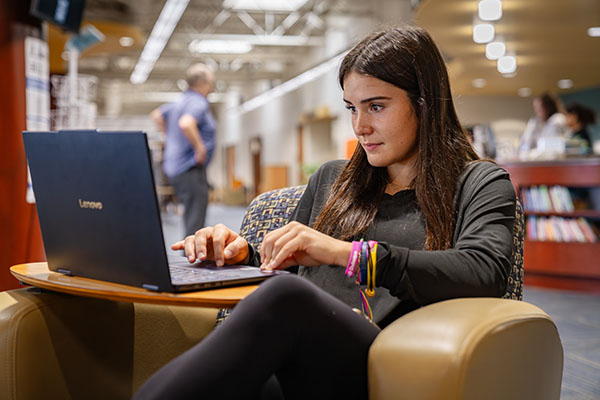 An NICC student working at her laptop in the Peosta Library.