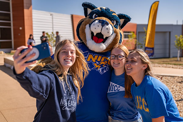 Three students pose with Chase the mascot.