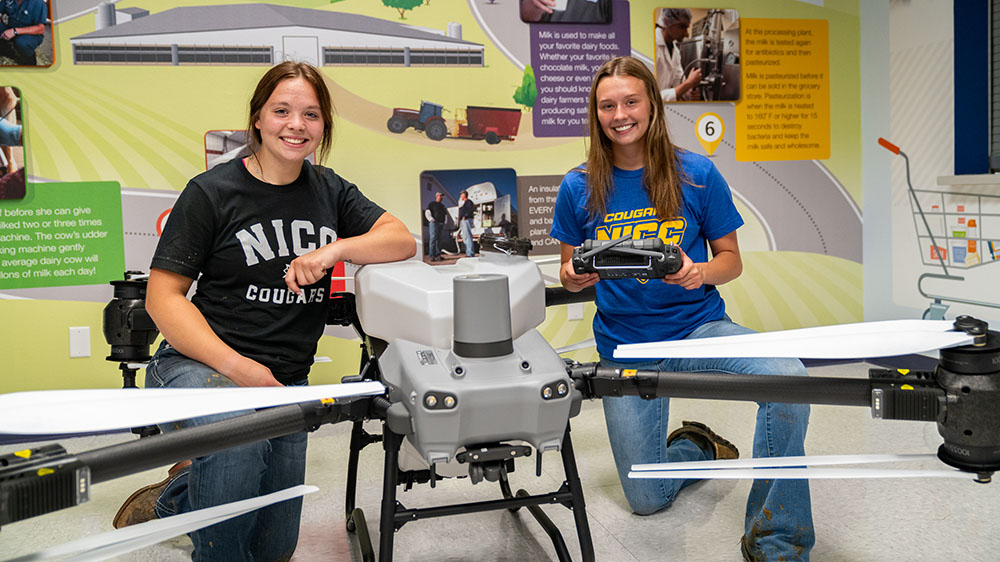 Two NICC agriculture students pose next to a drone.