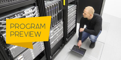 A data center technician inspects a rack of servers.