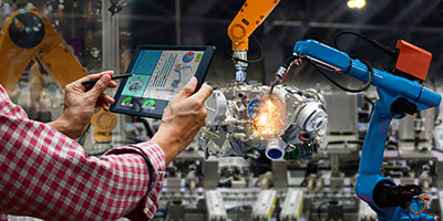 A person controls two manufacturing robots with a tablet.