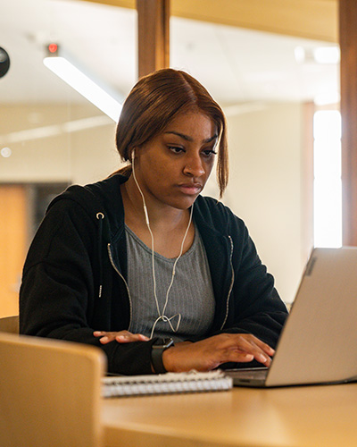 An NICC student working at her laptop in the Peosta library.