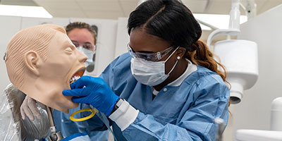 Female, African American student works on a dental dummy