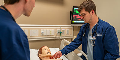 male healthcare student working on a mannequin