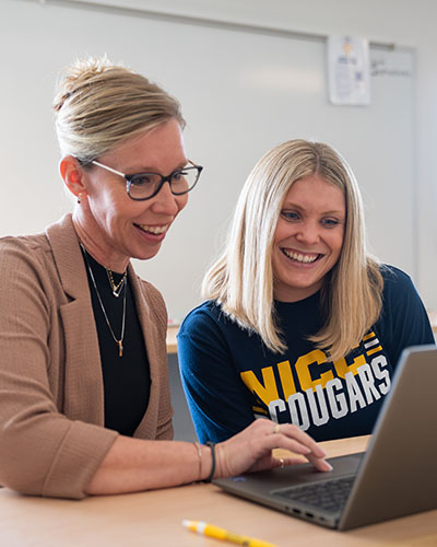 A BCS staff member helping a student while on a laptop.