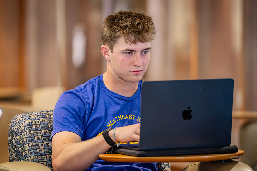 An NICC student working at his laptop in the Peosta Library.