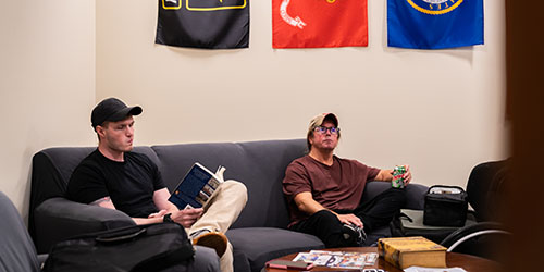 Two military students sit under military flags