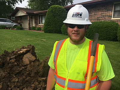 Graduate Tyler Monahan working on a utility line in a front yard.