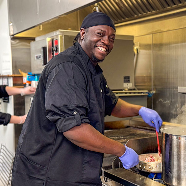 A chef mixing a pan on a stove top.