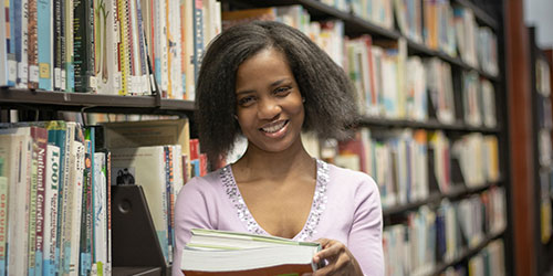 Female student poses in library stacks