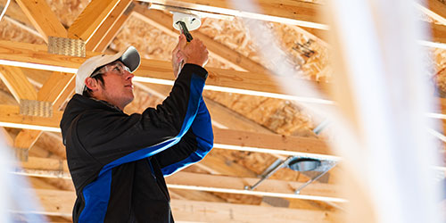 A male electrical student installs a light recess in a house.
