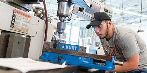 A male cnc student works at a lathe in the lab.
