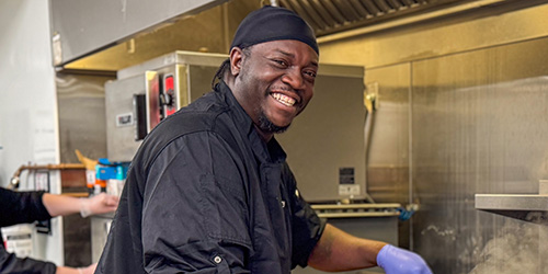 A chef mixing a pan on a stove top.