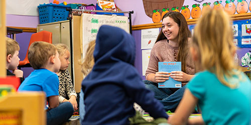 An early childhood student reads to children at the development center.