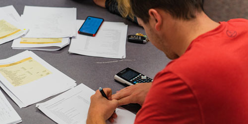 Male student works on his math homework with a calculator