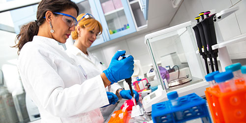 Two female lab technicians checking liquids in a lab.