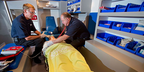 Two paramedic students work in the simulation ambulance.