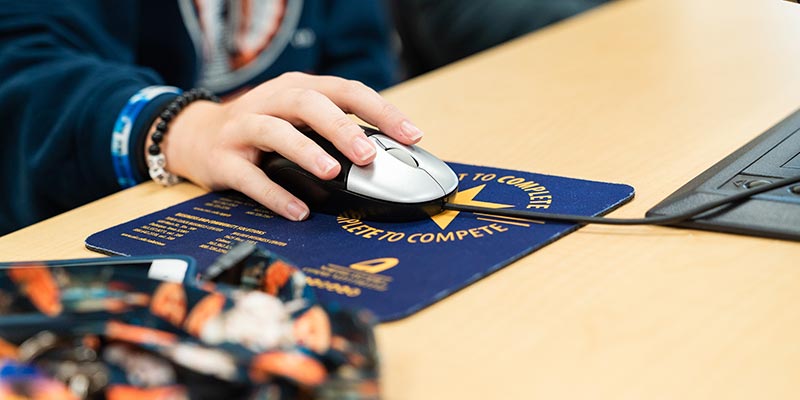 A student uses a mouse at a desktop in the computer lab.